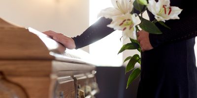 woman with lily flowers and coffin at funeral Giulio Riscaldino onoranze funebri a Torino e provincia