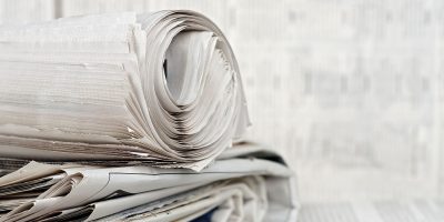 rolled newspaper on stack of newspapers against blurry background