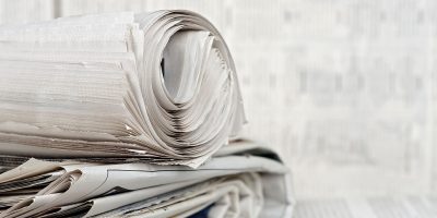 newspapers rolled newspaper on stack of newspapers against blurry background